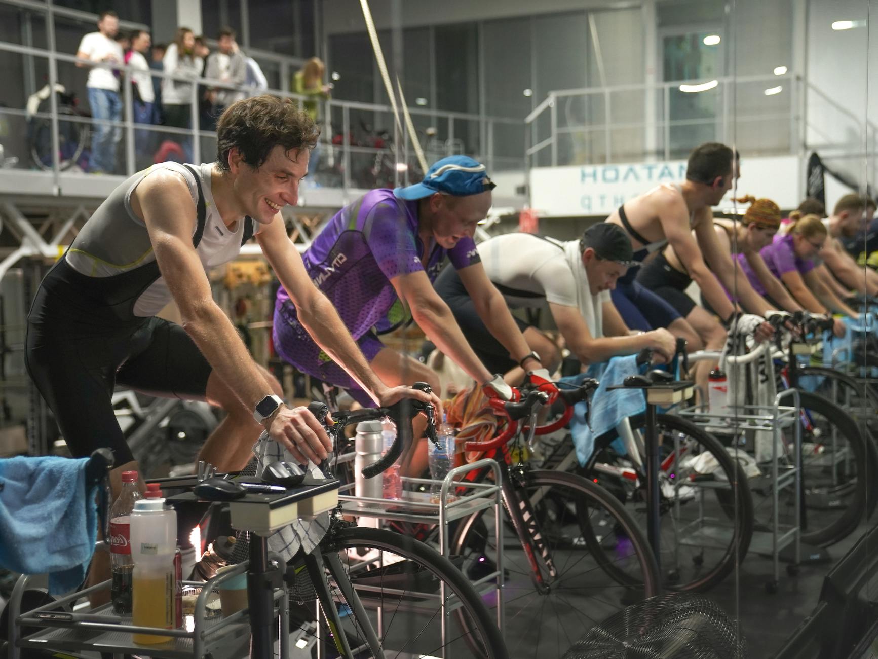 Grupa kolarzy trenujących na rowerach stacjonarnych na sali fitness
